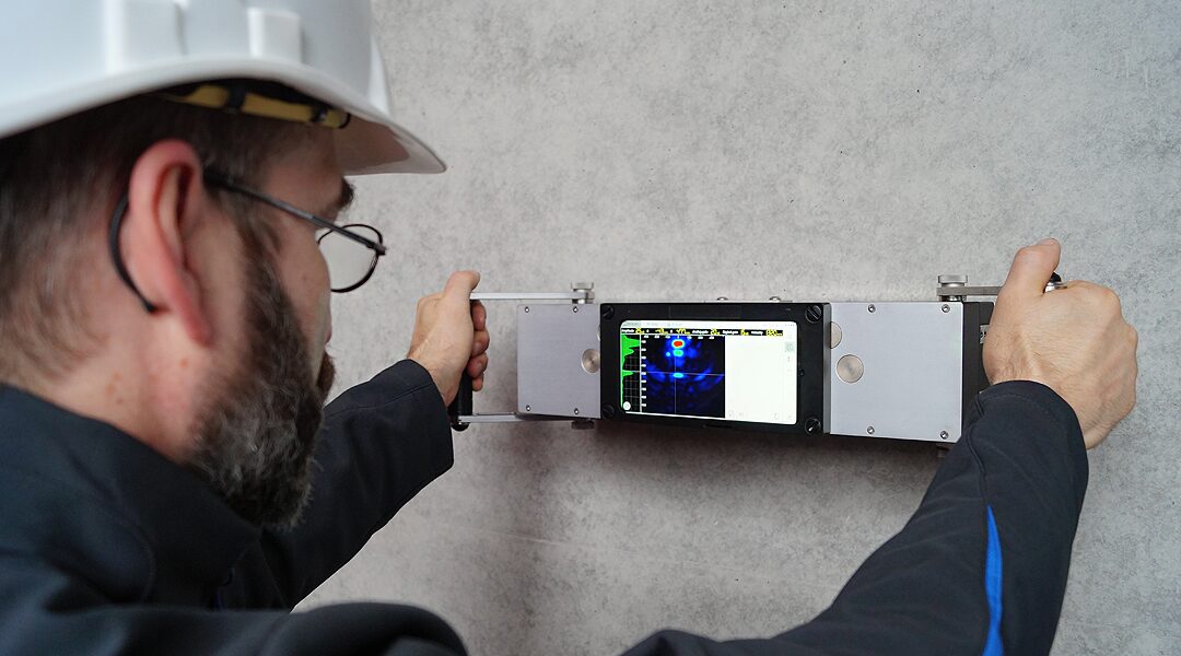 Operator menggunakan A1040 MIRA 3D Pro untuk pulse-echo tomography pada beton